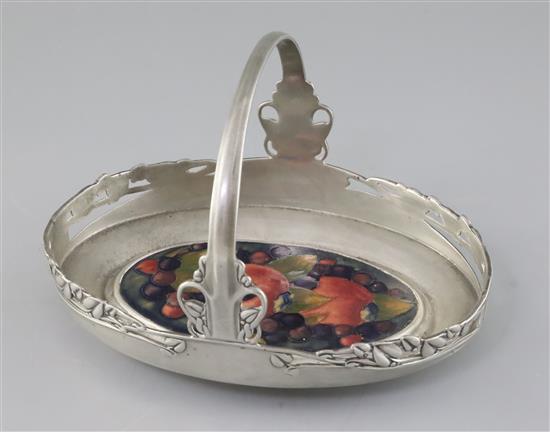 A rare Moorcroft pomegranate inset Tudric pewter cake basket, c.1920, designed by Archibald Knox, L.23.5cm